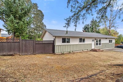 Rear exterior with a tall wood privacy fence, open lawn and a small deck landing at the back door