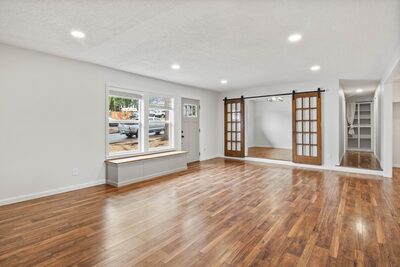 Living room with a built-in window bench and double sliding barn doors opening to the bonus room