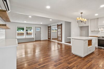 Kitchen island beneath a chandelier with a ductless mini split on the wall and a glass door to the hallway